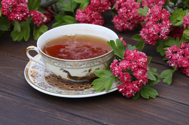 filiżanka herbaty na brązowym drewnianym tle z różowymi kwiatami