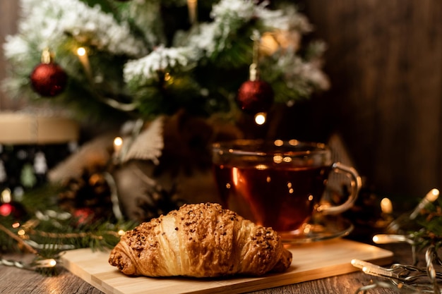 Filiżanka herbaty z croissantem w pobliżu choinki Nowy Rok w domu z rodziną