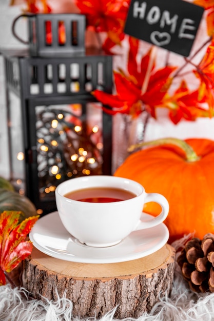 Filiżanka herbaty z cytryną, jesiennymi liśćmi i dynią. Koncepcja przytulnej jesiennej fotografii pionowej w domu. Zdjęcie wysokiej jakości