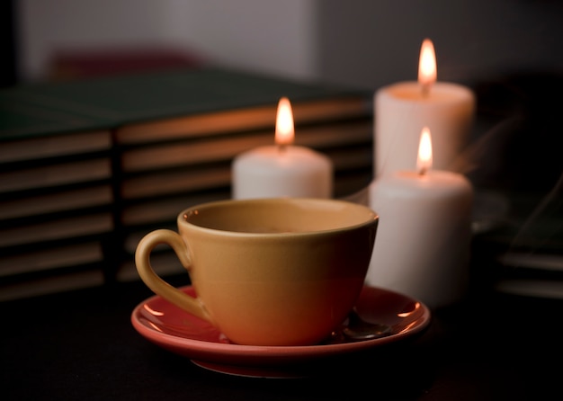 Zdjęcie filiżanka herbaty z gorącym dymem i trzy palące się świeczki na biurku w domu przerwa w dostawie prądu