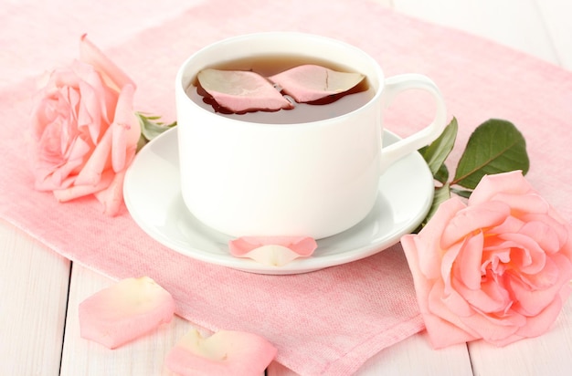 Filiżanka herbaty z różami na białym drewnianym stole