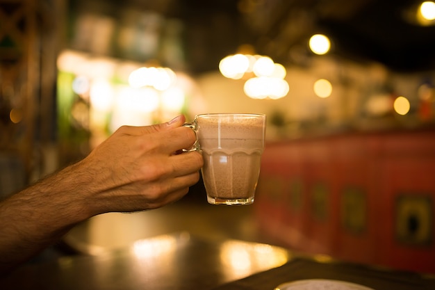 Filiżanka kakao w ręku, w kawiarni na tle świateł bokeh, w kawiarni