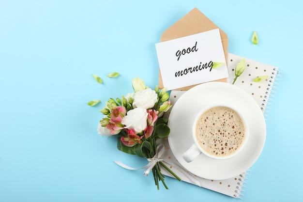 Filiżanka kawy bukiet kwiatów i kartka z napisem dzień dobry