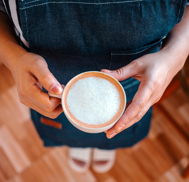 Zdjęcie filiżanka kawy cappuccino z menu gotowa do podania w ręce baristy w kawiarni