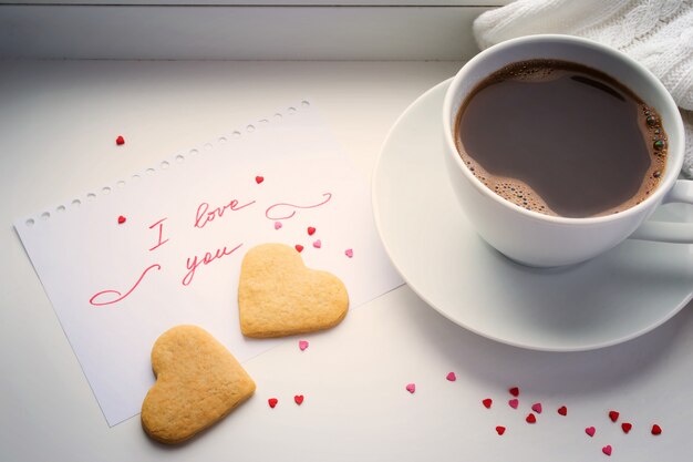 Filiżanka kawy, ciasteczka w kształcie serca i deklaracja miłości.