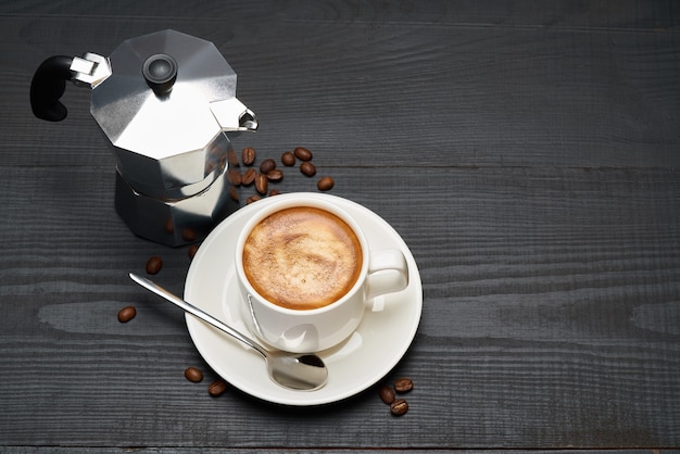 Filiżanka kawy espresso i ekspres do kawy mokka na ciemnym drewnianym stole