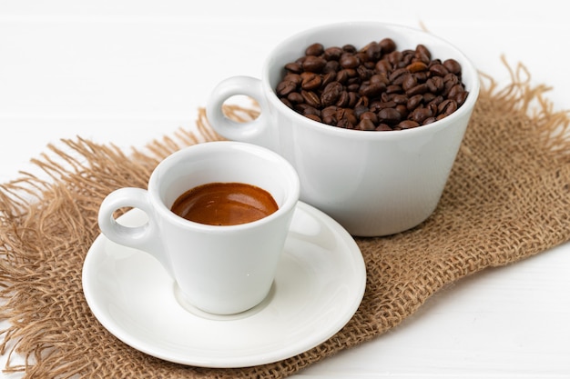 Filiżanka kawy espresso i ziaren kawy na białej powierzchni