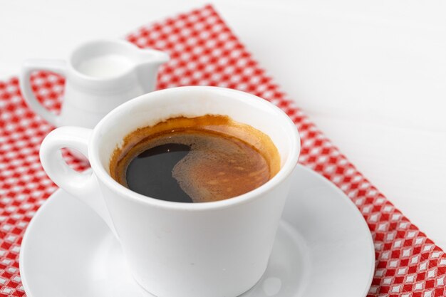 Filiżanka kawy espresso na spodeczku z bliska na białym stole