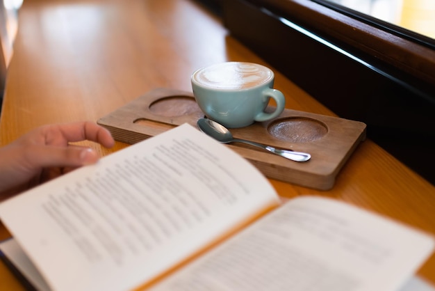 Filiżanka kawy i książka na parapecie przytulnej kawiarni