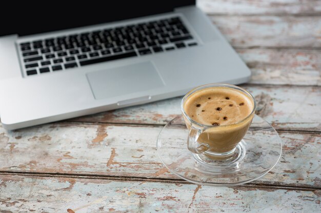 Zdjęcie filiżanka kawy i laptop na drewnianym stole