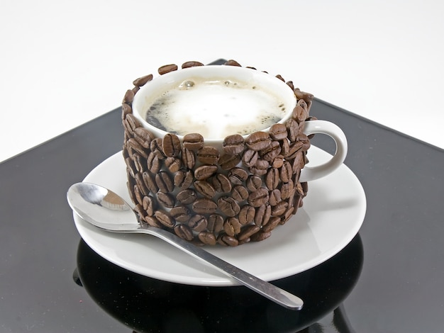 Zdjęcie filiżanka kawy i łyżka, ozdobione ziarnami kawy. odosobniony