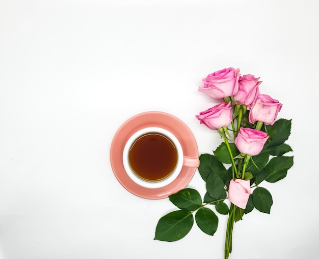 Filiżanka kawy i róż na białym tle