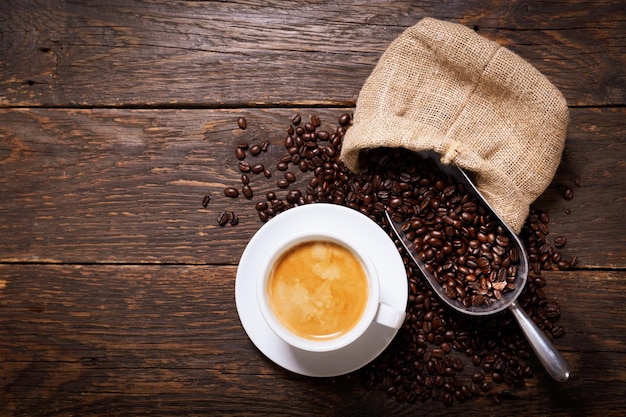 Filiżanka kawy i ziaren kawy na podłoże drewniane