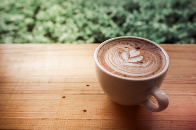 Filiżanka kawy latte art z sercem w białej filiżance z zieloną ramką urlopu