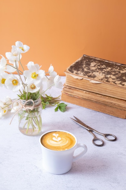 Filiżanka kawy latte i anemony bukiet kwiatów i książki vintage Wiosna Dzień Matki lub 8 marca kompozycja martwej natury