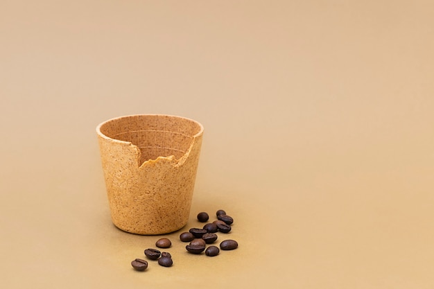 Filiżanka kawy lub herbaty z palonymi ziarnami kawy na beżowym tle jadalne kubki jako nowy trend zero waste