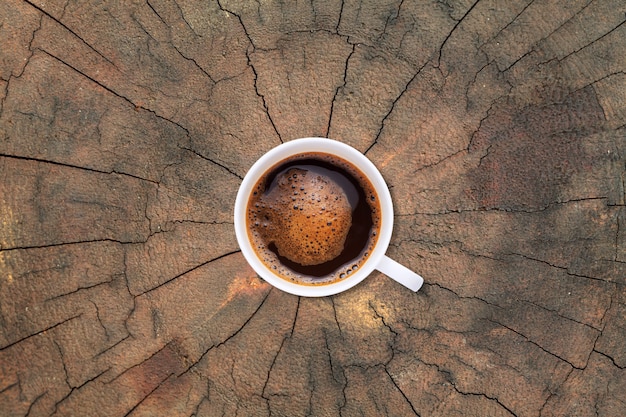 Filiżanka kawy na starym tekstury pnia drzewa tle