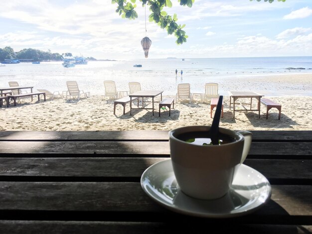 Zdjęcie filiżanka kawy na stole na plaży na tle nieba