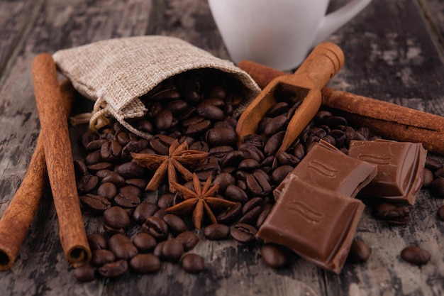 Filiżanka kawy z czekoladowymi laskami cynamonu i ziarnami kawy na drewnianym tle