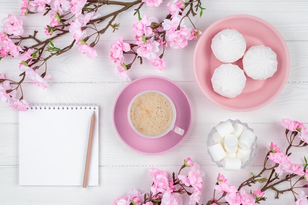 Filiżanka kawy z marshmallow rano na śniadanie. Pusty notatnik z piórem. Pamiętnik, koncepcja planowania. Romantyczna wiosna makieta z miejsca na kopię. Kwiat wiśni na białym tle drewnianych. Leżał płasko.