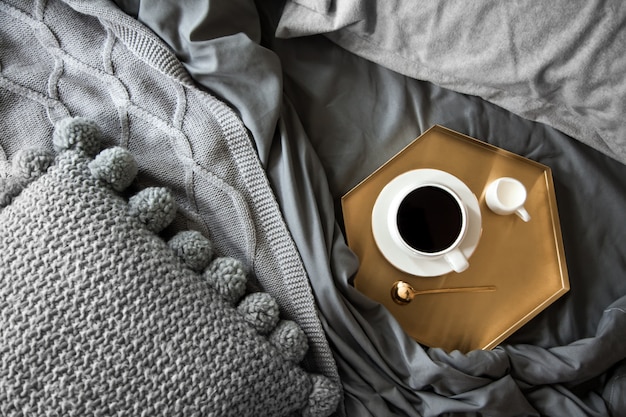 Filiżanka kawy z mlekiem na tacy w łóżku