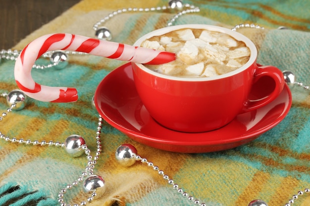 Filiżanka kawy z świątecznymi cukierkami na zbliżeniu w kratę