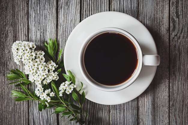 Zdjęcie filiżanka kawy z wiosennymi kwiatami na drewnianym stole z wysokim kątem strzału