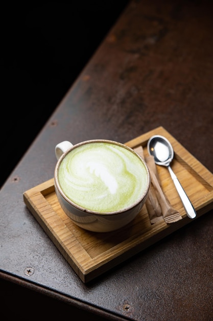 Filiżanka matcha latte z łyżką na drewnianej tacy