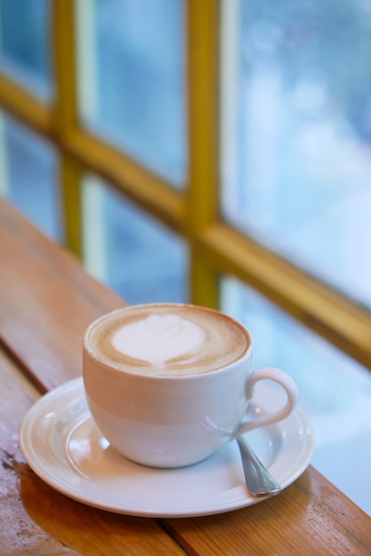 Filiżanka późnej kawy z motywem kwiatowym na górze w kawiarni