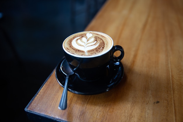 Filiżanka pysznego cappuccino z latte art na tle drewniany stół.