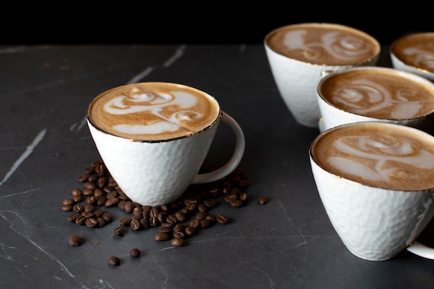 Filiżanki kawy stoją na marmurowym stole w kawiarni latte art na kawie z ziarnami kawy