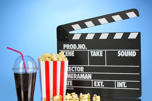 Film clapperboard cola i popcorn na niebieskim tle