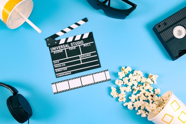 Zdjęcie film clapperboard popcorn film strip retro videotape słuchawki i szkło papierowe na niebieskim