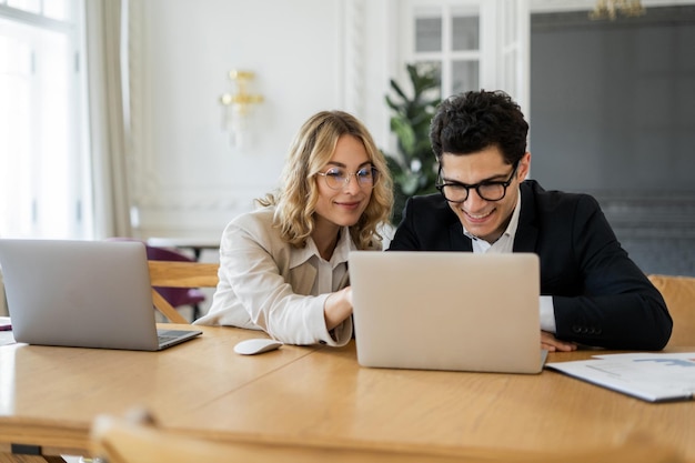 Finansiści mężczyzna i kobieta pracują razem w biurze nad projektem online Korzystaj z laptopów