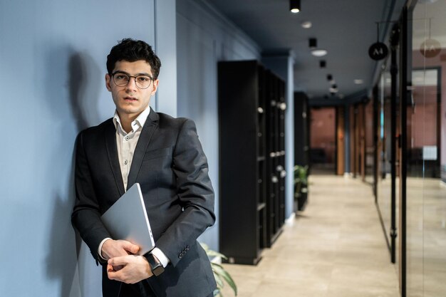 Finansista w okularach mężczyzna w formalnym ubraniu pracuje w biurze w coworkingu z laptopem