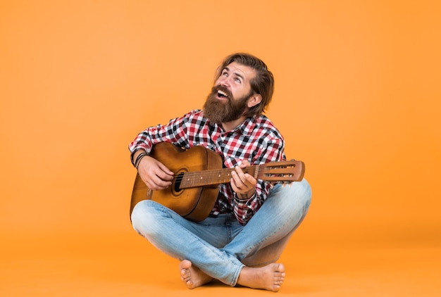 Fing the melody play string instrument muzyczny profesjonalny kaukaski muzyk gitarzysta hipster mężczyzna gra na gitarze akustycznej w stylu muzyki country mężczyzna ubrany w kraciastą koszulę i trzymający gitarę
