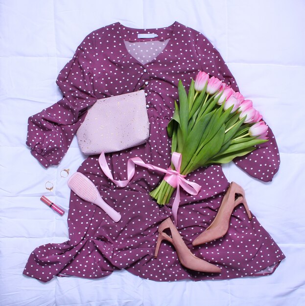 Fioletowa sukienka, beżowe buty na obcasie, błyszczyk, szczotka do włosów, bukiet różowych tulipanów