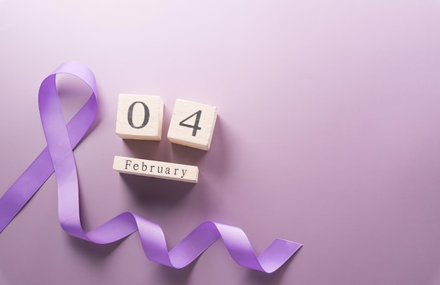 Fioletowa wstążka i drewniany kalendarz na tle pastelowego papieru za wsparcie kampanii Światowego Dnia Walki z Rakiem 4 lutego
