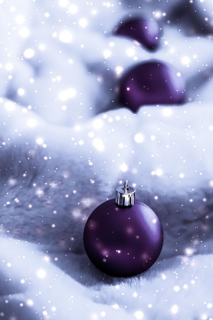 Fioletowe bombki na puszystym futerku ze śniegiem brokatowym luksusowym zimowym wzorem wakacyjnym w tle