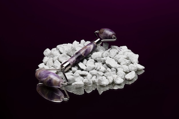 Zdjęcie fioletowe narzędzie gua sha o wysokim kącie na kamykach