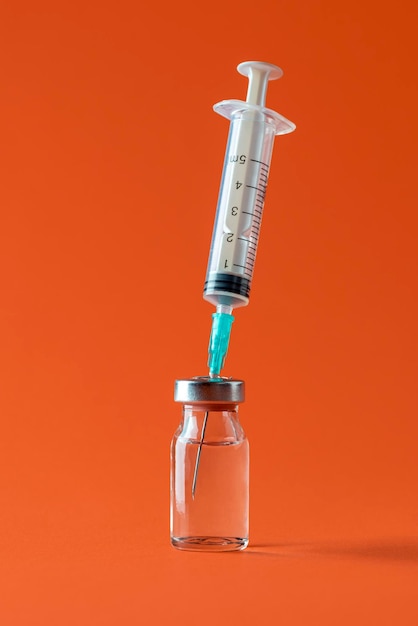 Fiolka szczepionki ze strzykawką wyizolowaną na pomarańczowym tle