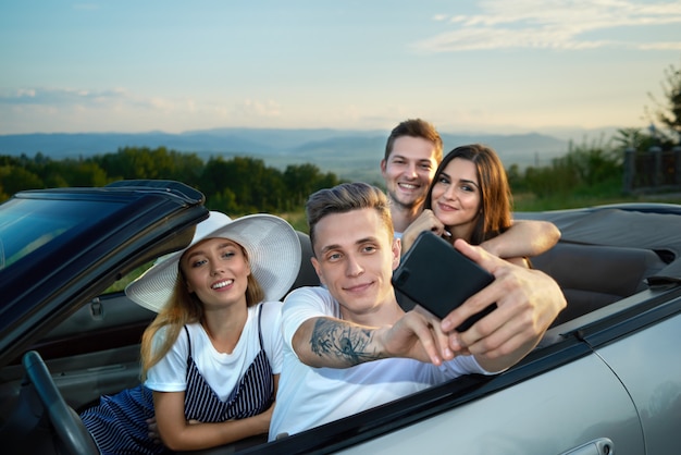 Firma robi selfie siedząc w kabriolecie.