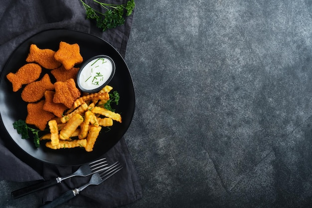 Fish Chips Brytyjskie Fast Food Paluszki Rybne z frytkami na czarnym talerzu na czarnym tle stołu Tradycyjne brytyjskie autentyczne jedzenie uliczne lub jedzenie na wynos Makieta z miejscem na tekst