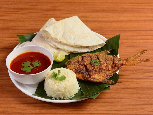Fish thali z kuchni indyjskiej składa się z smażonej ryby pomfret na parze z soczewicy ryżowej i selektywnej ostrości roti