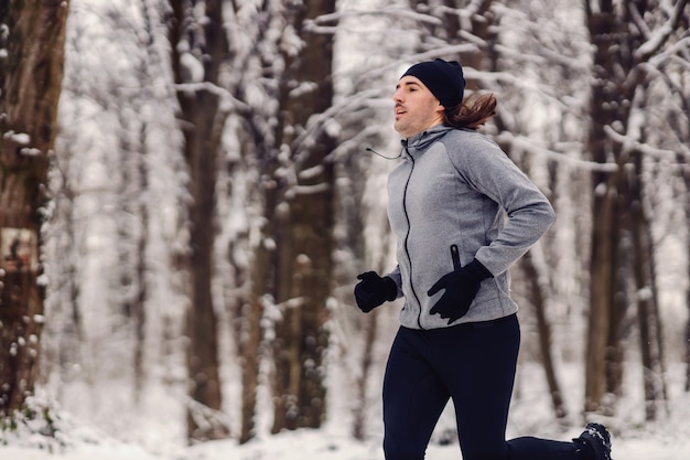 Fit biegacz biegający w lesie na śniegu w zimie. Fitness na świeżym powietrzu, sporty zimowe, ćwiczenia cardio