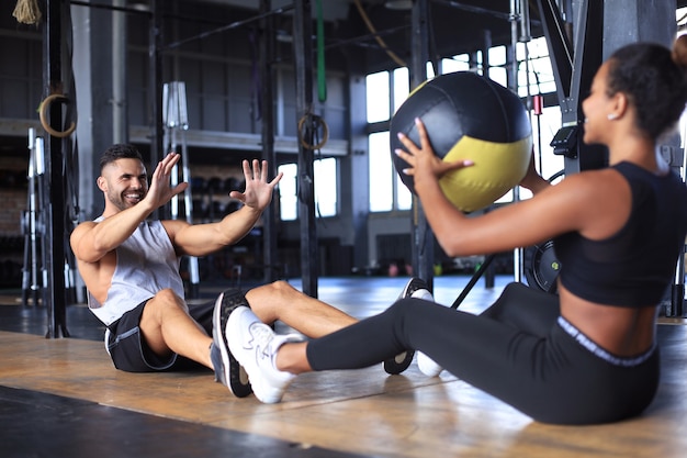 Fit i muskularna para ćwiczenia z piłką lekarską na siłowni.