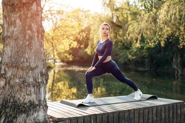 Fit młoda kobieta ćwiczy na macie w parku