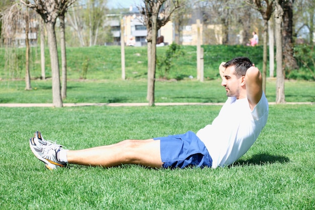 fitness człowiek ćwiczenia siedzieć na zewnątrz w trawie w lecie.