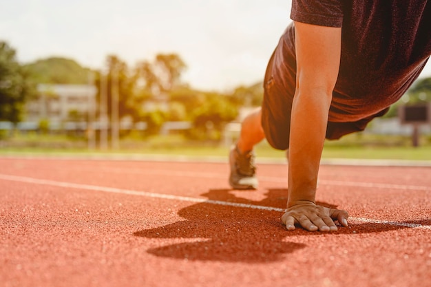 Fitness, jogging, bieganie, ćwiczenia, styl życia i zdrowa koncepcja. Młody człowiek nosił wszystkie części ciała, aby przygotować się do biegania na bieżni wokół boiska piłkarskiego.