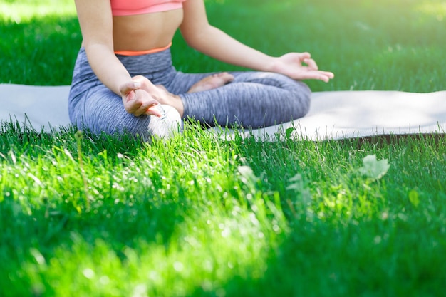 Fitness, kobieta joga relaks medytacja w pozycji lotosu na zewnątrz w parku, miejsce. Młoda szczupła dziewczyna sprawia, że ćwiczenia. Koncepcja rozciągania, odnowy biologicznej, spokoju, relaksu, zdrowego, aktywnego stylu życia